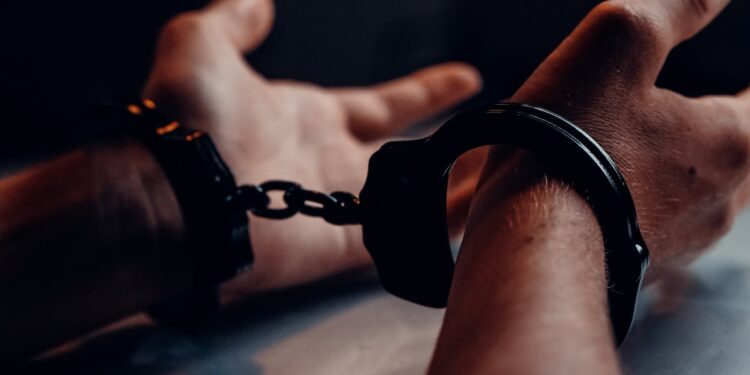 a person s hands on the table wearing handcuffs